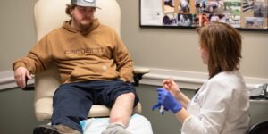 patient receiving wound care evaluation from doctor while sitting on chair