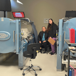 Patient and HBOT technician smiling by hyperbaric oxygen therapy chambers